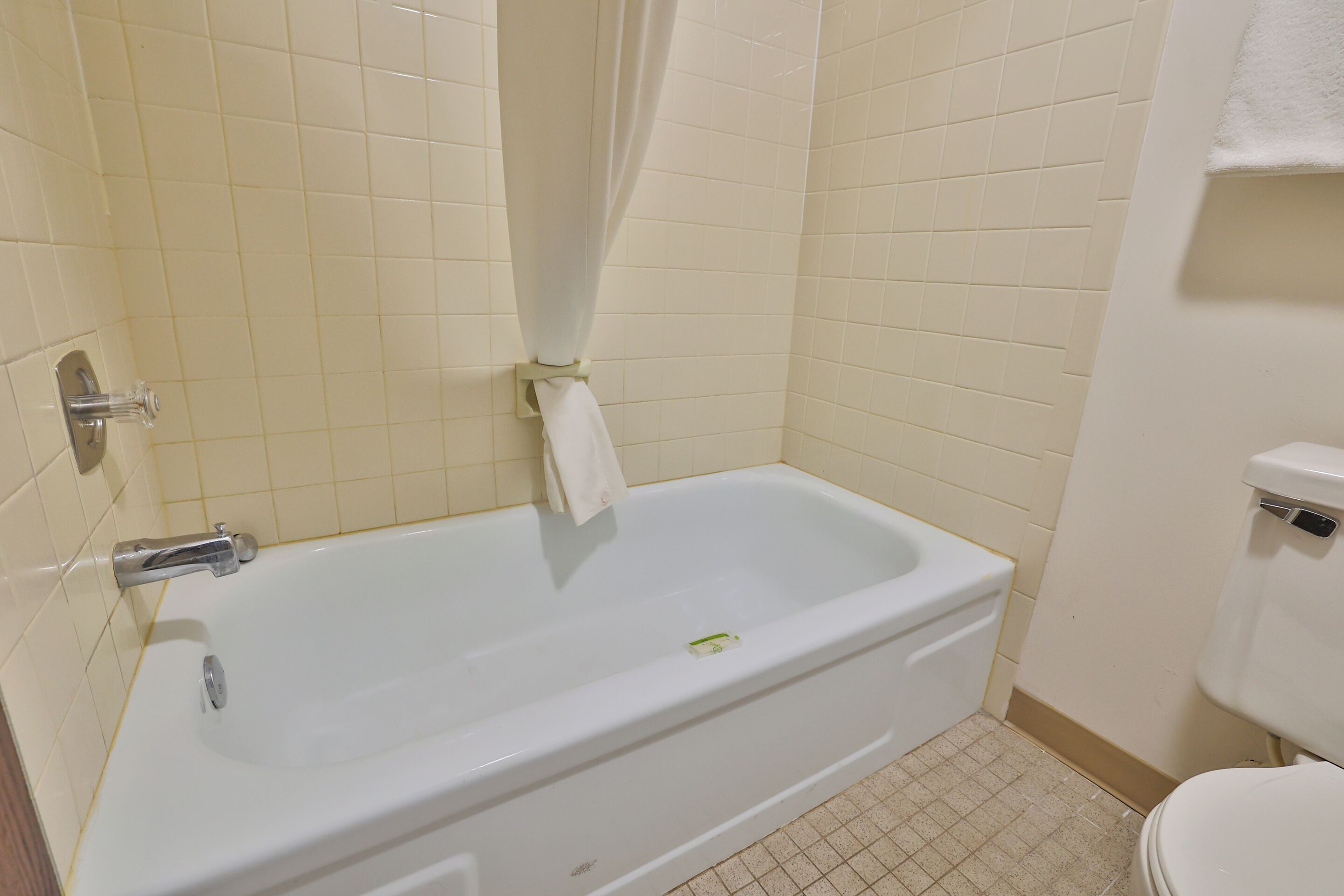 Une salle de bain avec une baignoire blanche, des toilettes et un rideau de douche.