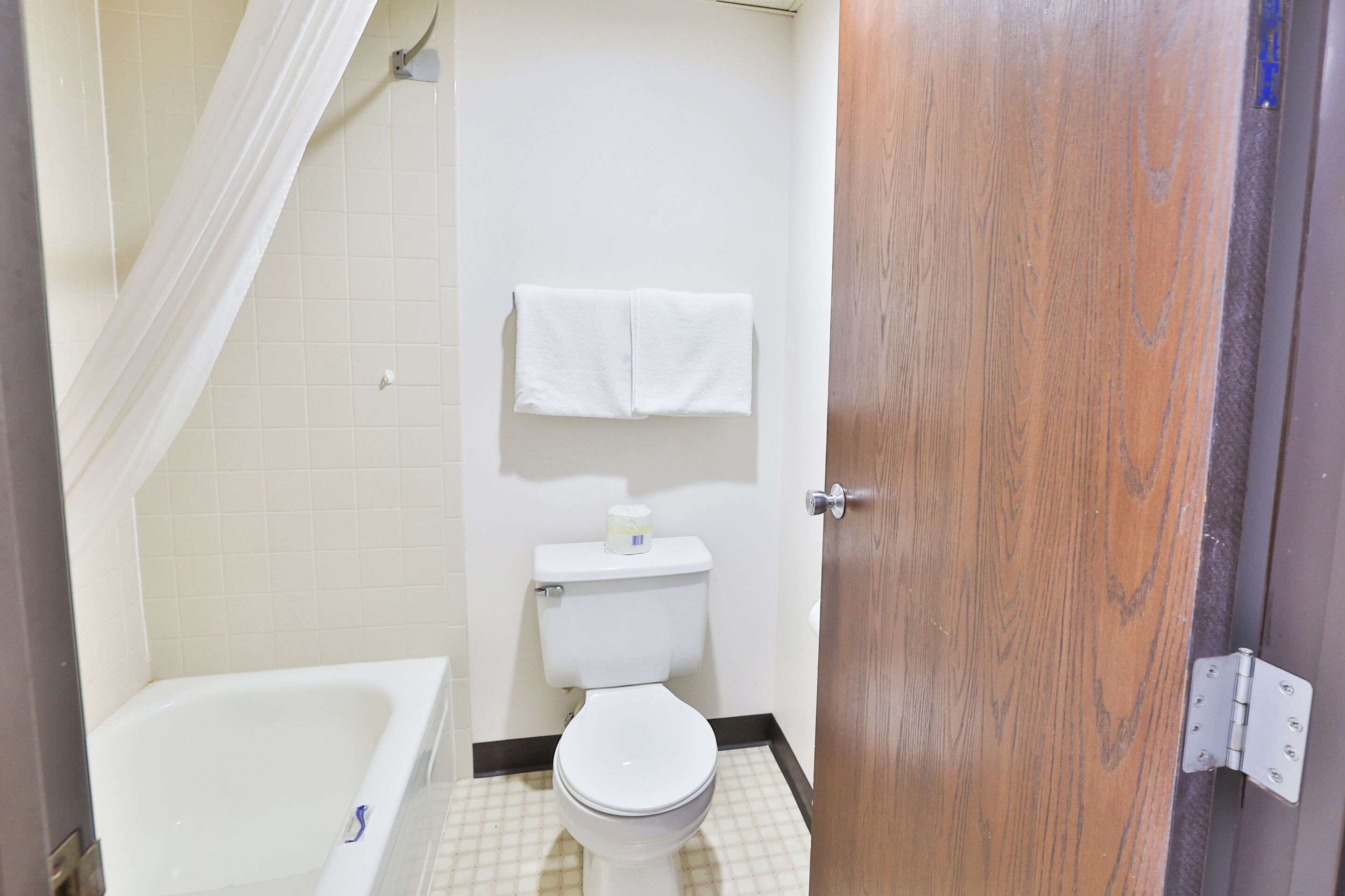 A small bathroom with a white bathtub, a toilet, and a wooden door.