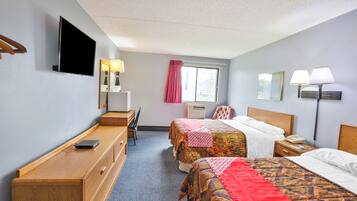 A hotel room with two beds, a desk, a chair, a TV, and a window with curtains.