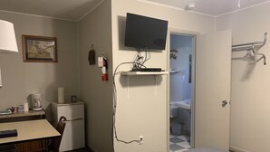 Een hotelkamer met een bureau, stoel, televisie en een kleine kitchenette.
