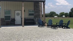 A building with a porch, outdoor seating, and a gravel driveway. - Grand Lake Barndominium. Close to Wolf Creek & Monkey Island. Lake access! (Afton)