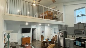 A spacious living area with a high ceiling, a dining table, and a kitchen area. - Grand Lake Barndominium. Close to Wolf Creek & Monkey Island. Lake access! (Afton)
