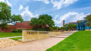 Trinity University's entrance with a stone wall, green lawn, and brick buildings. - Studio apartment with golf course view halfway between SA and Boerne (Boerne)