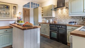 A kitchen with a central island, a stove, oven, and a brick backsplash. - 5 bedroom accommodation in Saham Toney (Saham Toney)