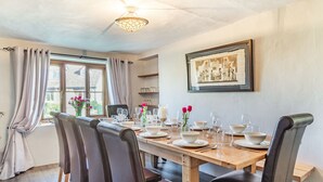 A dining room with a wooden table set for six, six chairs, and a framed picture on the wall. - 5 bedroom accommodation in Saham Toney (Saham Toney)