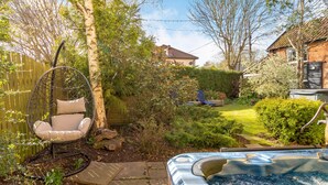 A backyard with a hot tub, a hanging chair, and a wooden fence. - 5 bedroom accommodation in Saham Toney (Saham Toney)