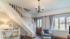 A spacious living room with a staircase, a glass coffee table, and a view through the window. - 5 bedroom accommodation in Saham Toney (Saham Toney)