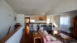A spacious living area with a wooden floor, a sofa, a dining table, and a kitchen in the background. - Modern 6 Bedroom Wildwood Beach Getaway (Wildwood Crest)