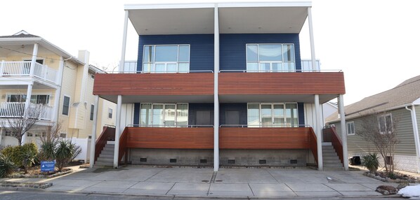 A two-story building with a wooden front porch and a balcony on the upper floor. - Modern 6 Bedroom Wildwood Beach Getaway (Wildwood Crest)