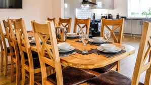 A dining area with a wooden table set for six, surrounded by wooden chairs. - 4 bedroom accommodation in Carlisle (Carlisle)