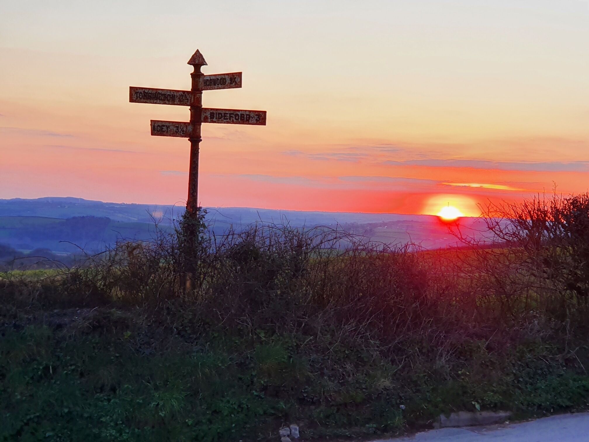 A rustic signpost with directional arrows pointing towards various destinations.