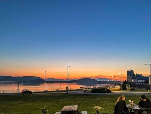 A sunset view with a grassy area, a table, and a few people sitting. - 2 bedroom accommodation in Oban (Oban)