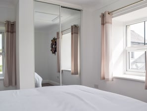 Un dormitorio con cama, ventana y espejo.