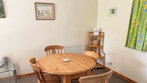 A round wooden table with four chairs, a small shelf with a clock, and a framed picture on the wall. - Chestnut Lodge - UK38194 (Bromham)