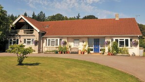A two-story building with a red-tiled roof, a blue front door, and potted plants around the entrance. - Chestnut Lodge - UK38194 (Bromham)