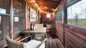 Une cabane en bois avec une table et des chaises en bois, un banc, une fenêtre et un sauna.