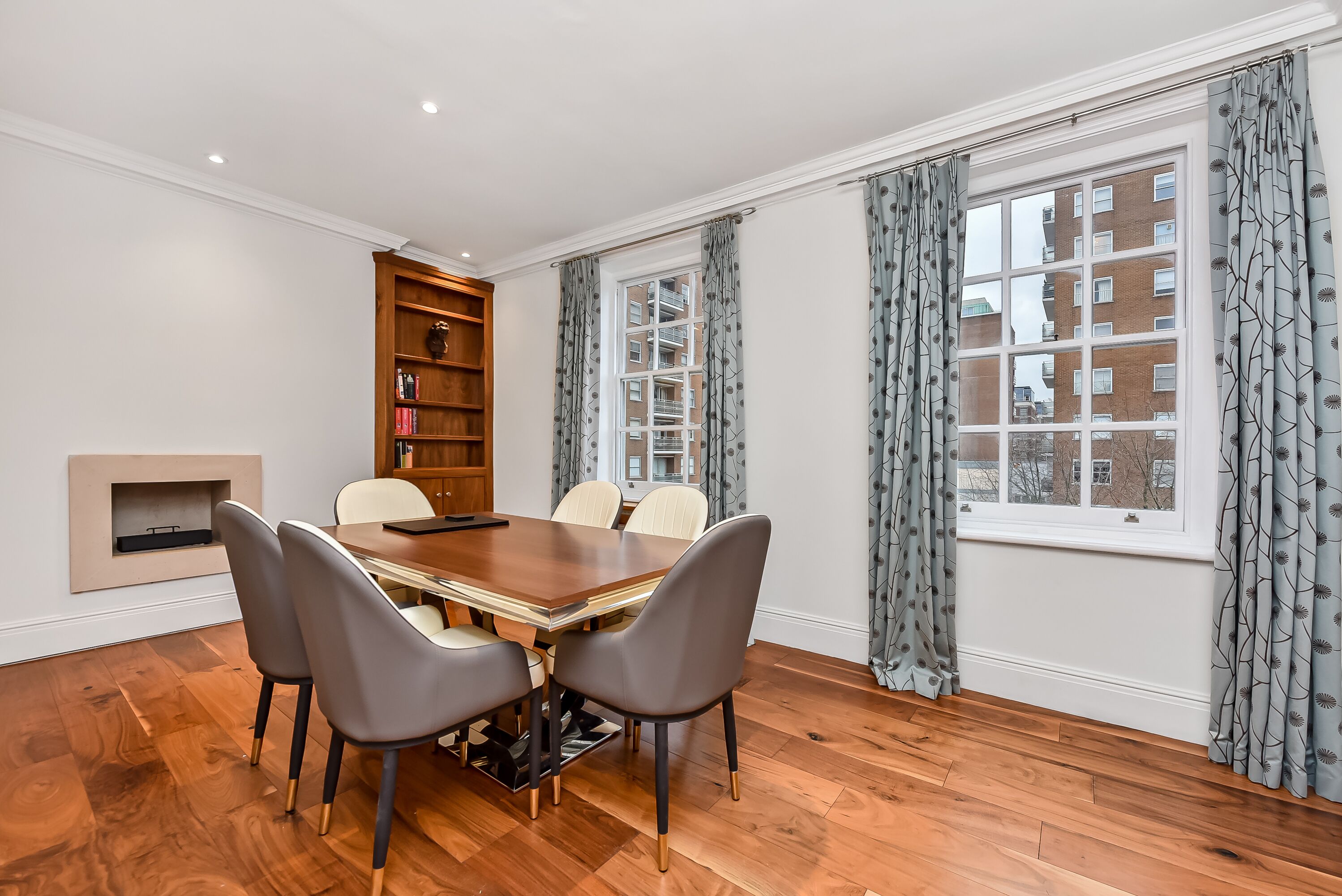 Un coin repas comprenant une table en bois, quatre chaises, une bibliothèque et une cheminée.