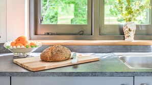 A kitchen counter with a loaf of bread, a bowl of fruit, and a potted plant. - 1 bedroom accommodation in Chiddingstone (Chiddingstone)