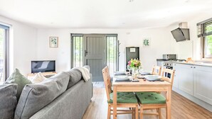 A modern living room with a sofa, dining table, and kitchen area. - 1 bedroom accommodation in Chiddingstone (Chiddingstone)