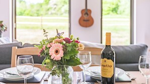 A dining table with a wine bottle, glasses, and a vase of flowers. - 1 bedroom accommodation in Chiddingstone (Chiddingstone)