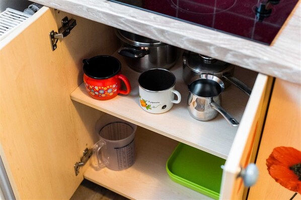 Un meuble de cuisine contenant divers ustensiles, notamment des tasses et des casseroles.