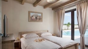 Una camera da letto con un letto di legno, un quadro appeso al muro e vista su una piscina.