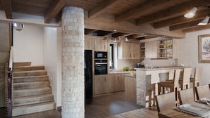 Una cucina moderna con mobili in legno, un'isola centrale e un pilastro in pietra.
