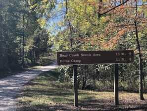 A signpost with directions to Bear Creek Scenic Area and Horse Camp, indicating distances of 1.5 miles and 1.1 miles respectively. - Big South Fork! Peaceful, Relaxing, On the Trails…Six Decks ~ Nature’s Paradise! (Strunk)
