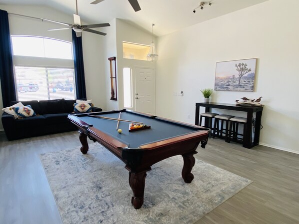 A pool table in a living room with a sofa and a dining area with chairs. - Beautiful, 3 bedroom , 2bath ,heated pool , pool table  (Avondale)