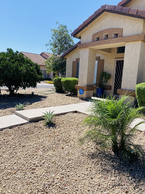 A residential building with a beige exterior, a covered porch, and a gravel driveway.