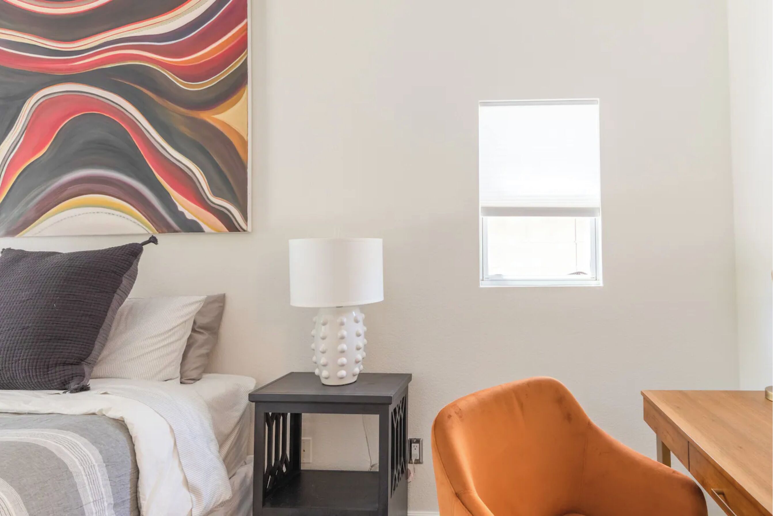 Une chambre à coucher avec un lit, une table de chevet avec une lampe, une chaise et une fenêtre.