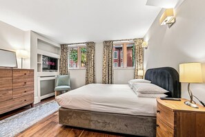 A hotel room with a bed, a chair, a TV, a dresser, and a window with curtains. - Stylish two bedroom apartment with sofa bed (London)