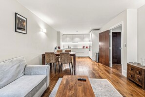 A modern living room with a sofa, coffee table, and dining area with chairs.