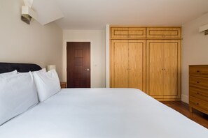 A bedroom with a bed, a wooden wardrobe, and a dresser.