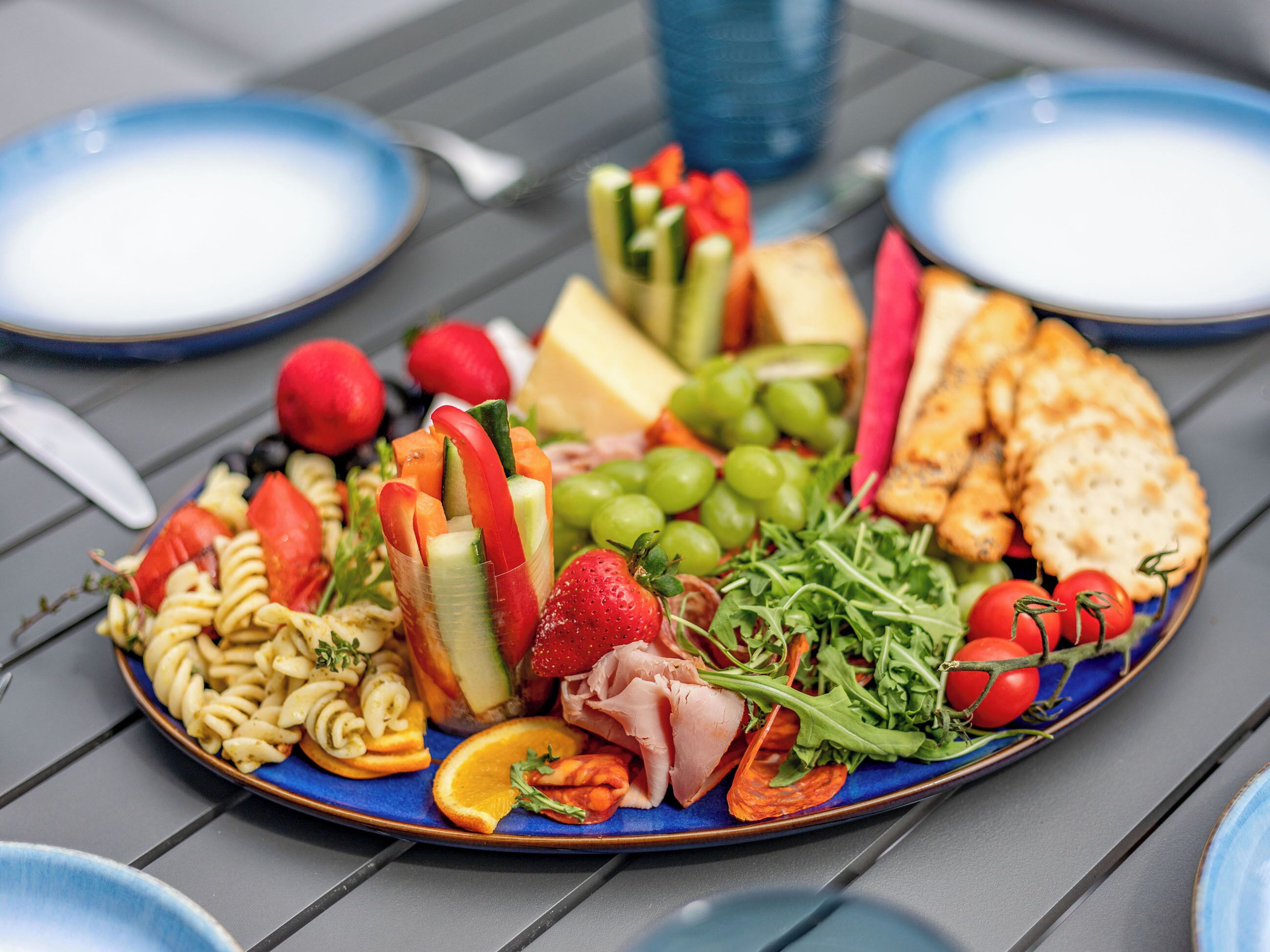 A table with a variety of food items including pasta, cheese, meats, and vegetables.