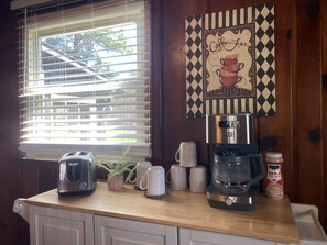 Una encimera de cocina con una cafetera, un tostador y una taza de café.