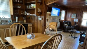 Un intérieur de chalet chaleureux comprenant un coin repas, une cuisine et un salon.