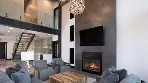 A spacious living area with a fireplace, modern furniture, and a staircase leading to an upper level. - Big Sky Luxury Estate, Mountain Views, 6 Bed 6.5 Bath, Private Lodge, Ski in/out (Big Sky)