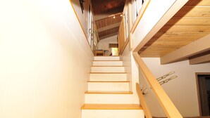 Un escalier avec des marches en bois et une rampe, menant à une pièce dotée d’une porte et d’une fenêtre.