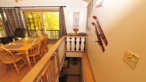 Un coin repas avec une table et des chaises en bois, un escalier avec une rampe et un porte-skis fixé au mur.