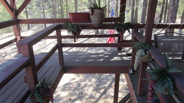 A wooden deck with railings, potted plants, and a flag.