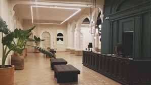 Un vestíbulo amplio con mostrador de recepción, zona de estar y grandes plantas en macetas.