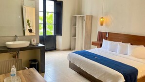 Una habitación de hotel con cama, mesita de noche, lavabo y espejo.