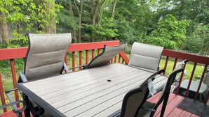 A wooden deck with a table and chairs, surrounded by a red railing and greenery. - Spacious and comfortable single family home with finished basement. (Reynoldsburg)