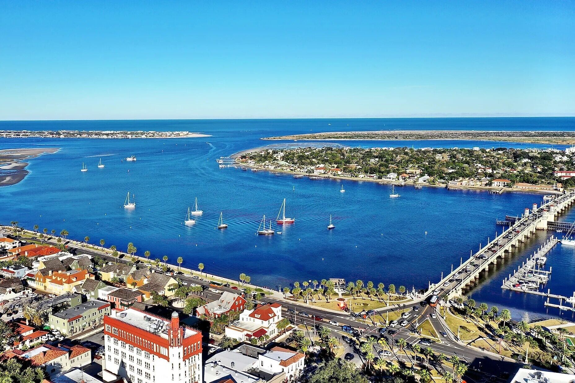 A coastal town with a marina, buildings, and a bridge.