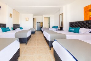Ett hotellrum med fyra sängar placerade i en rad, en garderob och en spegel på väggen.