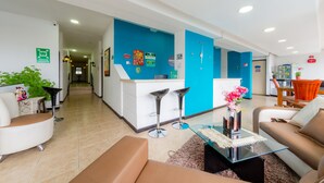 Eine moderne Hotelhalle mit einer Rezeption, einer Sitzecke und einer Treppe zu den anderen Etagen.