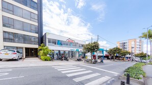 Ein Hotel mit moderner Fassade, einem gut sichtbaren Eingang und einem Parkplatz mit mehreren Autos und Motorrädern.