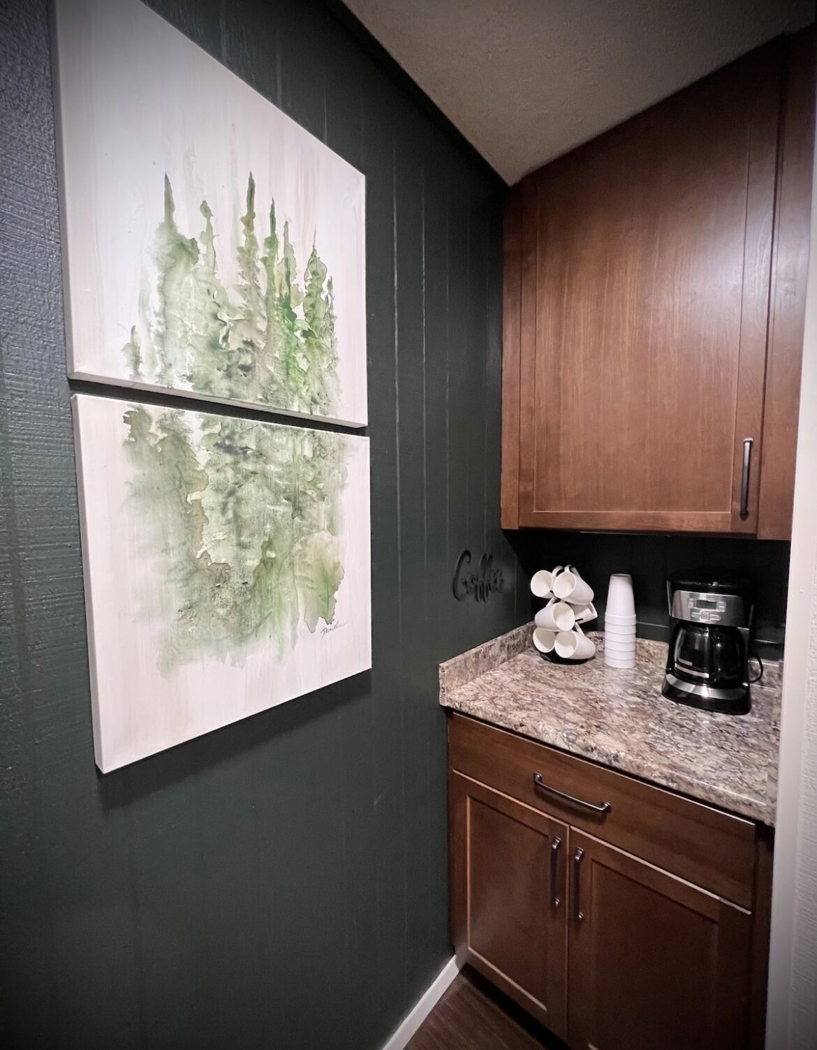A kitchen with dark wooden cabinets, a granite countertop, and a coffee maker.