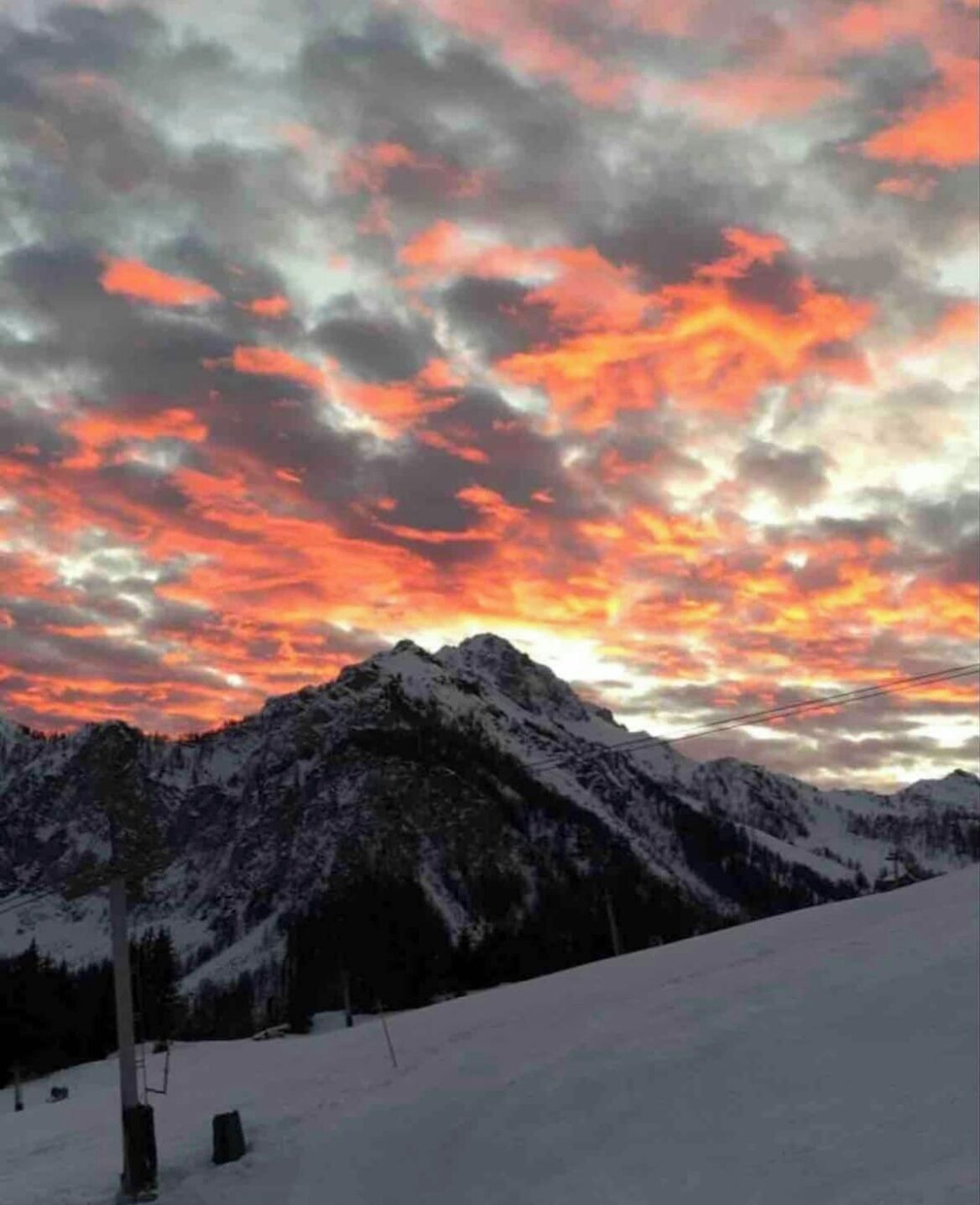 A snow-covered mountain range with a sunset sky.